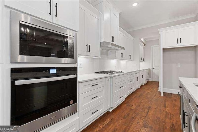 kitchen with dark wood-type flooring, stainless steel appliances, crown molding, and white cabinets