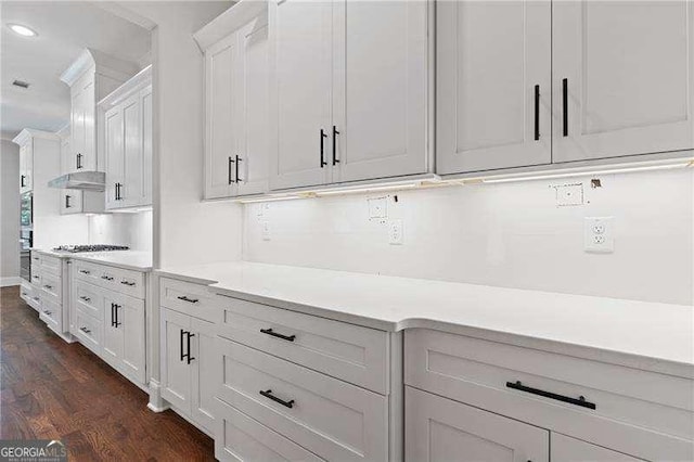 kitchen featuring stainless steel oven, wall oven, dark hardwood / wood-style floors, and white cabinets