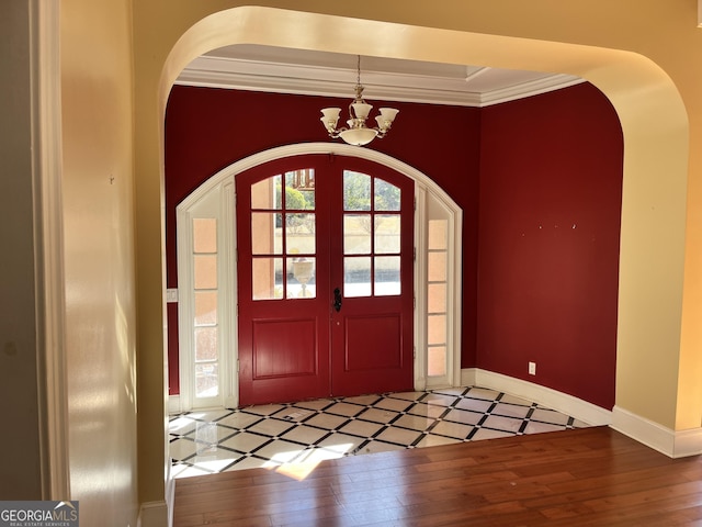 foyer featuring wood-type flooring, ornamental molding, and a chandelier