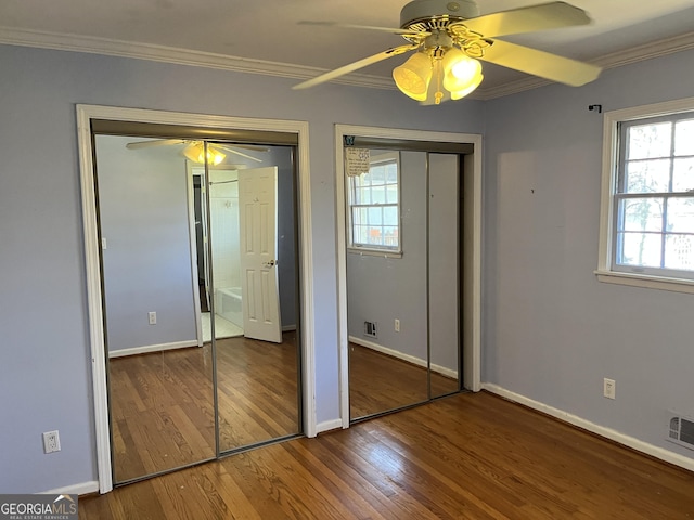 unfurnished bedroom with multiple closets, crown molding, hardwood / wood-style flooring, and ceiling fan