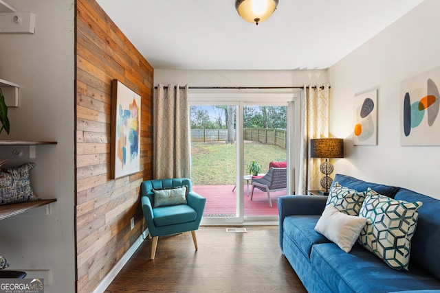 living room with dark wood-type flooring and wood walls