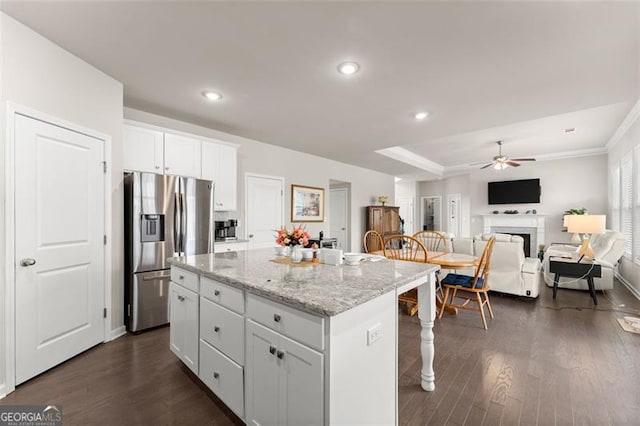 kitchen featuring stainless steel fridge with ice dispenser, light stone countertops, a center island, and white cabinets