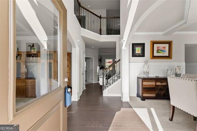 foyer featuring hardwood / wood-style flooring, ornamental molding, decorative columns, and a high ceiling