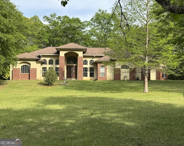 view of front of home with a front yard, a shingled roof, and stucco siding