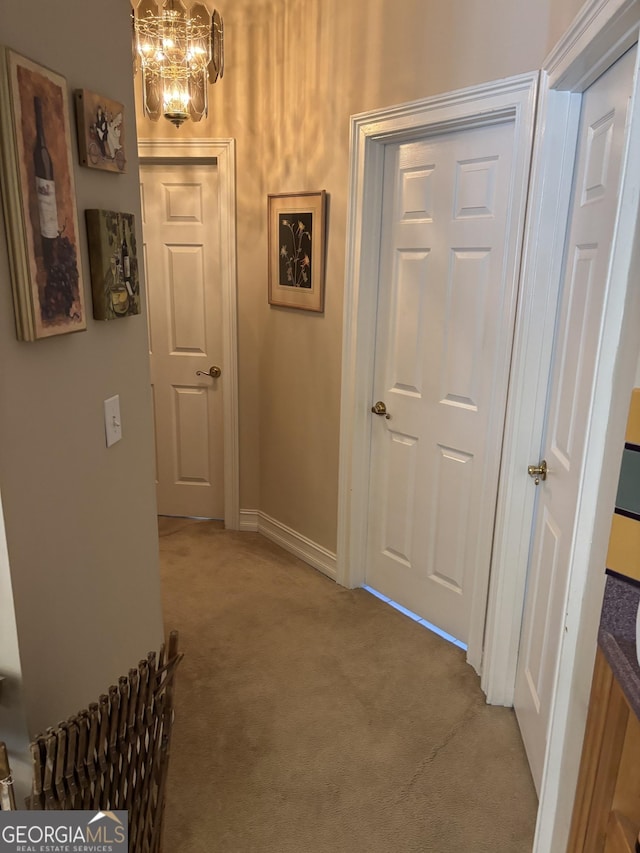 hallway with a chandelier and light colored carpet