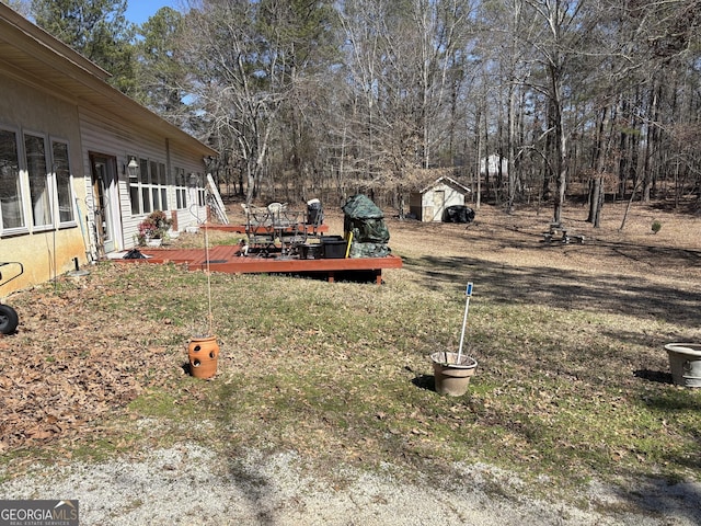 view of yard with an outbuilding, a wooden deck, and a storage unit