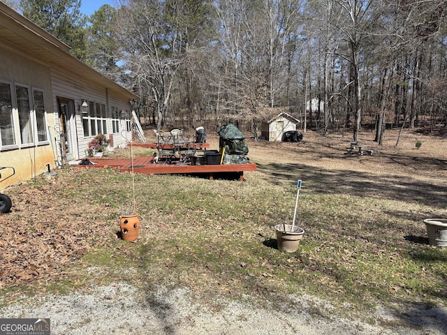 view of yard with an outdoor structure, a deck, and a shed