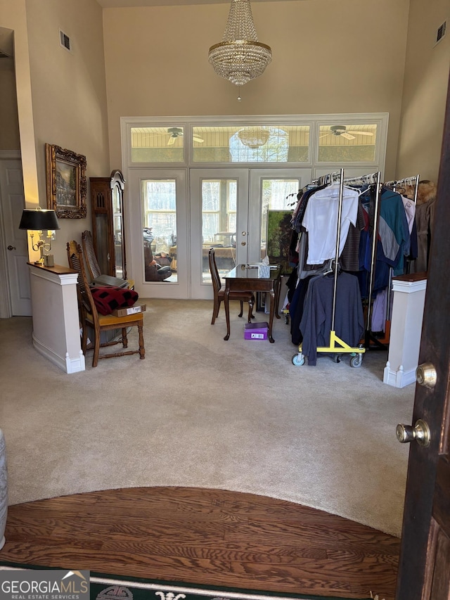 interior space with french doors, visible vents, a towering ceiling, and an inviting chandelier