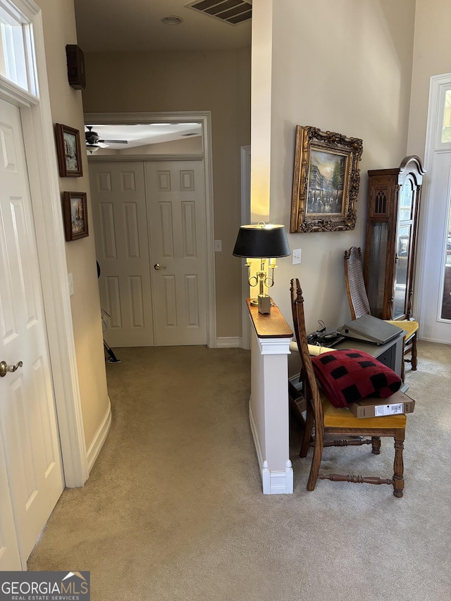 corridor with baseboards, visible vents, and light colored carpet