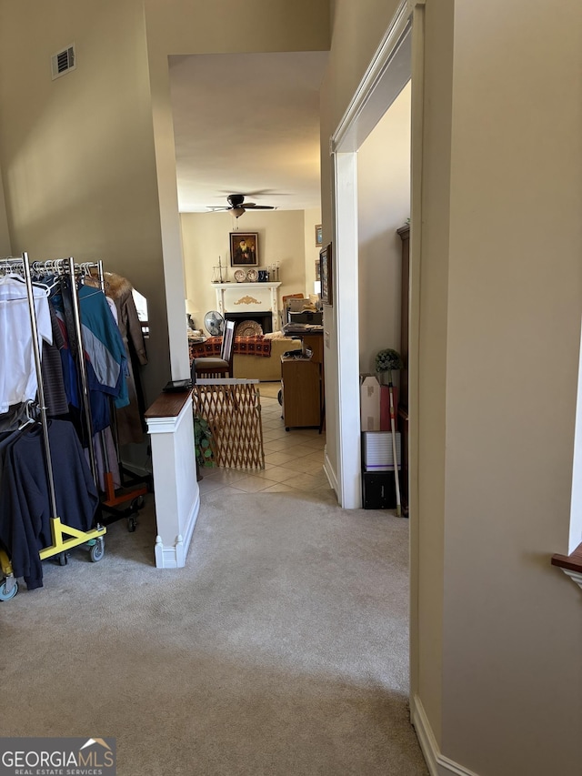 hallway featuring baseboards, visible vents, and light colored carpet