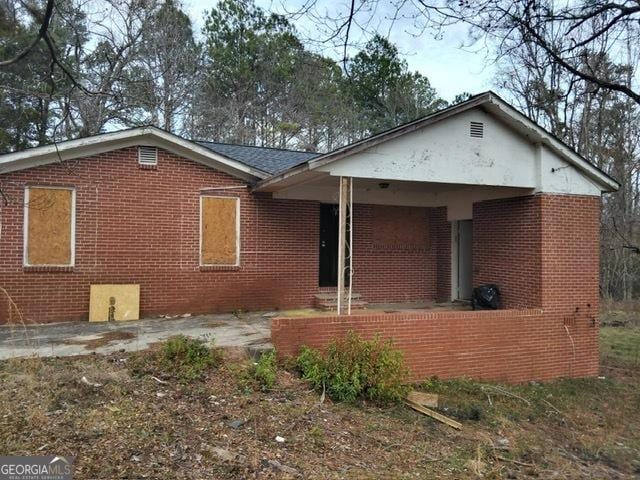 back of property with brick siding and a porch