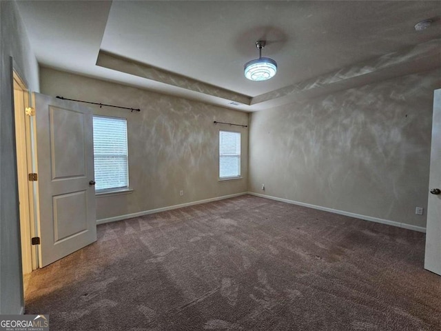 carpeted spare room with a raised ceiling