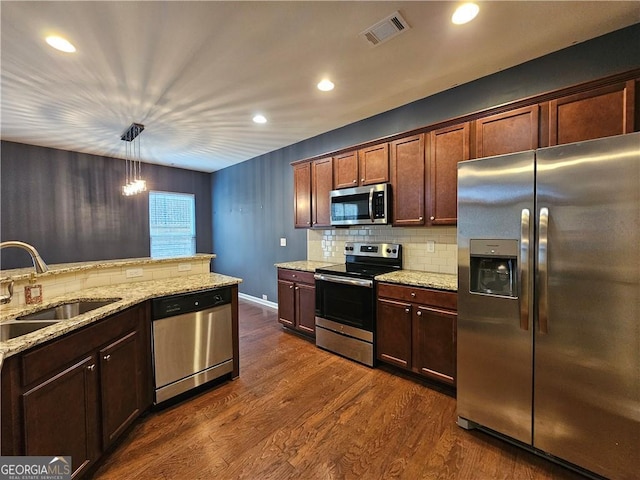 kitchen featuring sink, backsplash, hanging light fixtures, stainless steel appliances, and dark wood-type flooring