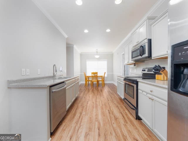 kitchen with sink, light hardwood / wood-style flooring, ornamental molding, stainless steel appliances, and white cabinets