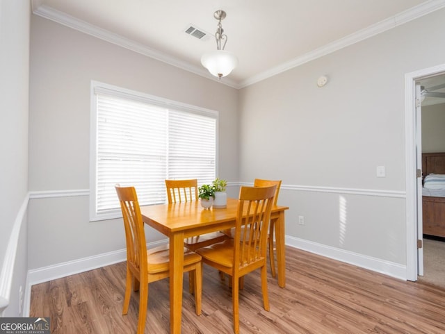 dining room with crown molding and light hardwood / wood-style floors