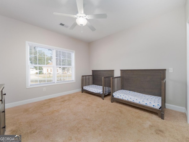 carpeted bedroom with a nursery area and ceiling fan