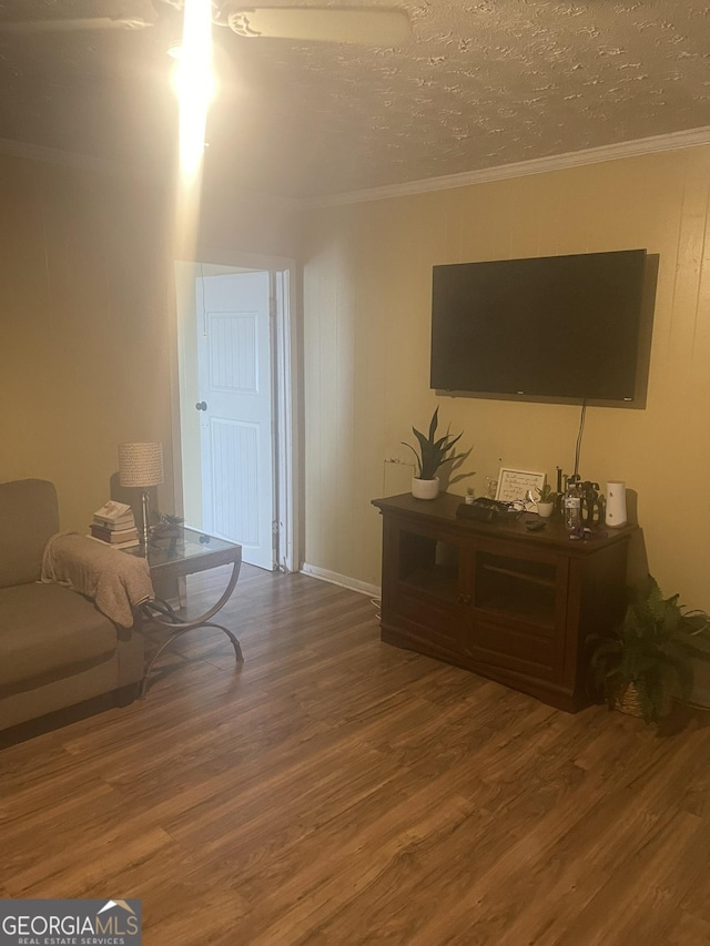 living room with hardwood / wood-style flooring, ornamental molding, and a textured ceiling