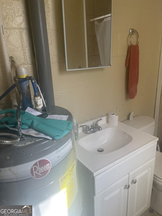 bathroom with water heater, vanity, and toilet