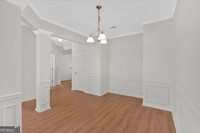 unfurnished dining area with a notable chandelier, ornamental molding, decorative columns, and light wood-type flooring