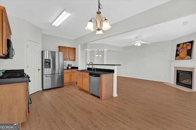 kitchen featuring sink, decorative light fixtures, an island with sink, stainless steel appliances, and light hardwood / wood-style floors