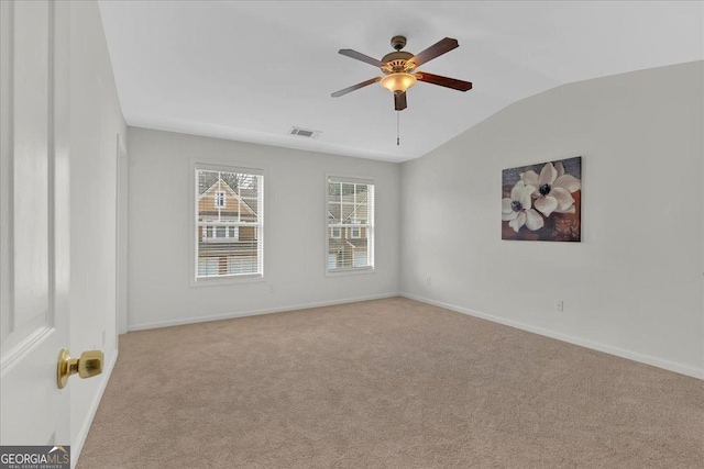 spare room featuring light carpet, lofted ceiling, and ceiling fan