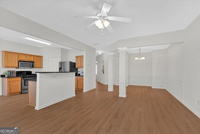 kitchen featuring decorative light fixtures, a center island, light wood-type flooring, stainless steel appliances, and decorative columns