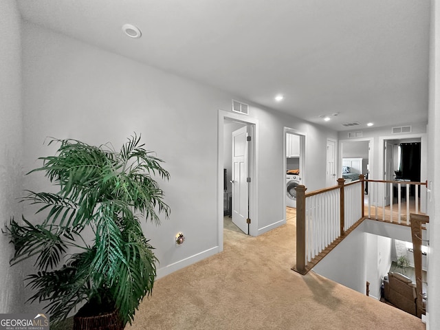 hall featuring washer / dryer and light carpet