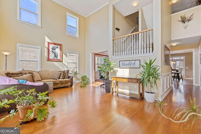 living room with crown molding, ornate columns, wood-type flooring, and a high ceiling