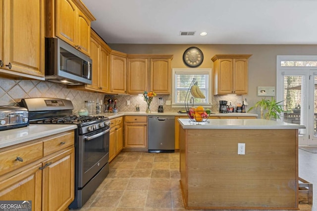 kitchen featuring stainless steel appliances, plenty of natural light, a center island, and sink