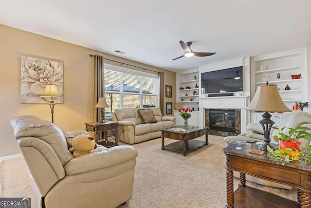 living room with built in shelves, carpet floors, a premium fireplace, and ceiling fan