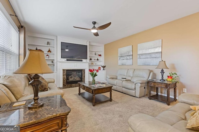 living room featuring built in shelves, ceiling fan, a fireplace, and carpet floors