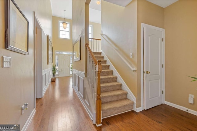 staircase with hardwood / wood-style flooring and a high ceiling