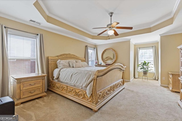 carpeted bedroom with crown molding, ceiling fan, and a tray ceiling