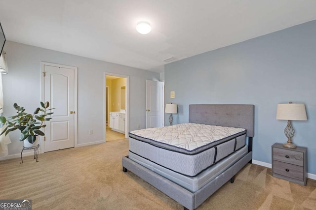 bedroom with connected bathroom and light carpet