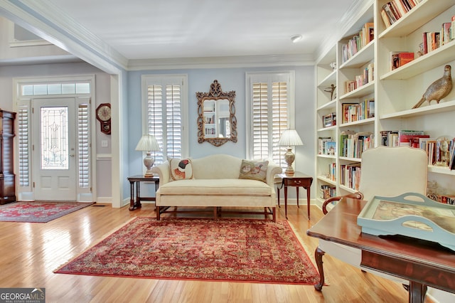 living area with light hardwood / wood-style flooring and ornamental molding