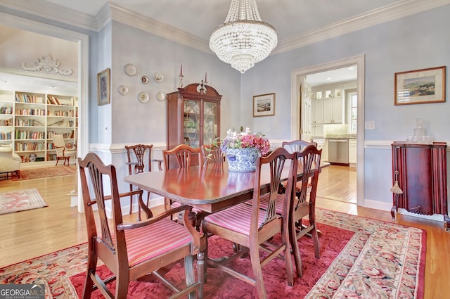 dining space featuring ornamental molding, light wood-type flooring, and a chandelier