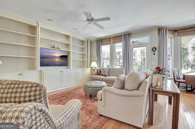 living room with ceiling fan, ornamental molding, light hardwood / wood-style floors, and built in features