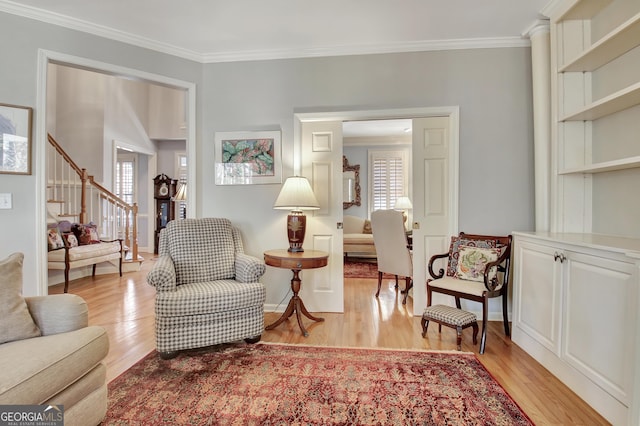 living area featuring crown molding, a healthy amount of sunlight, and light hardwood / wood-style floors