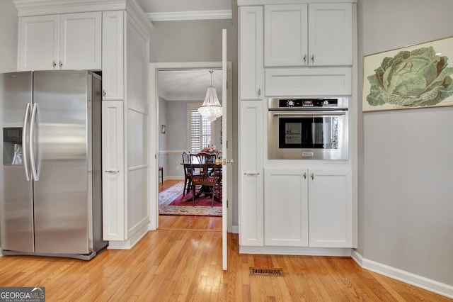 kitchen with light hardwood / wood-style flooring, appliances with stainless steel finishes, ornamental molding, white cabinets, and decorative light fixtures