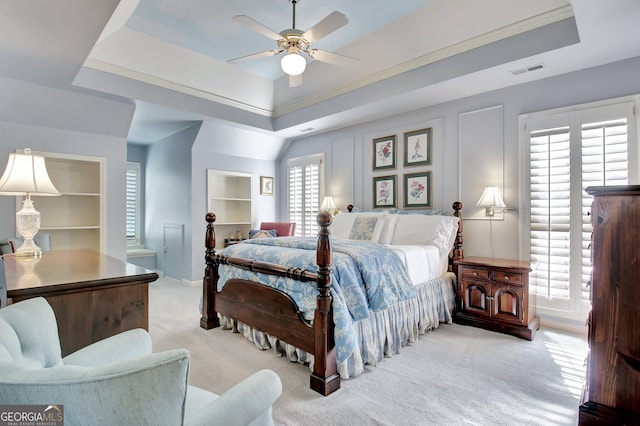 carpeted bedroom with crown molding, ceiling fan, and a tray ceiling