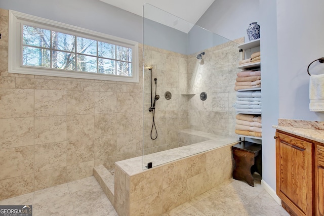 bathroom featuring vanity, lofted ceiling, and tiled shower