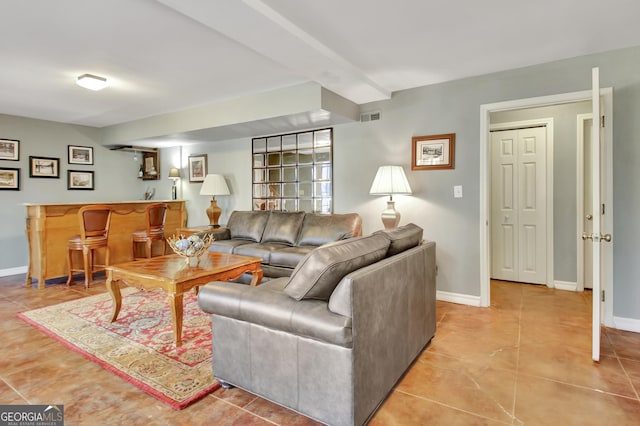 living room featuring light tile patterned floors, beam ceiling, and indoor bar