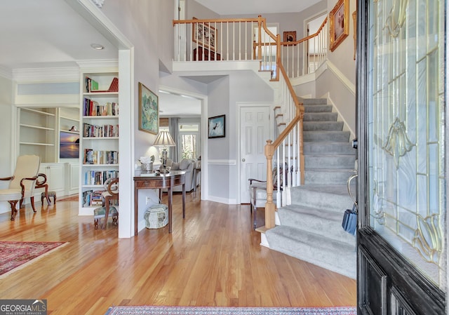 foyer with crown molding, hardwood / wood-style flooring, and a high ceiling