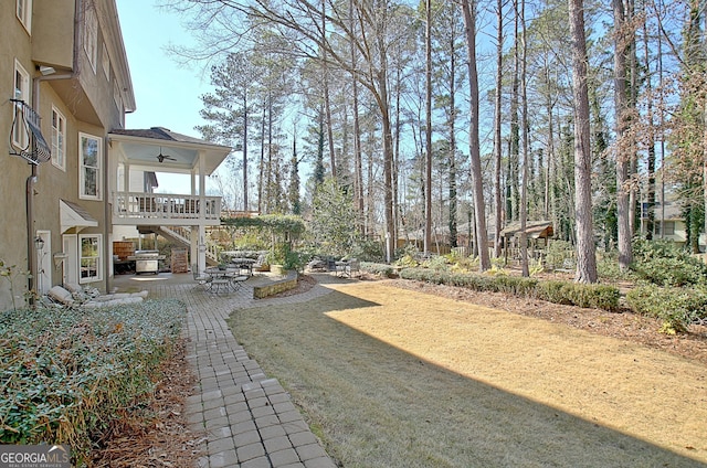 view of yard with ceiling fan, a balcony, and a patio