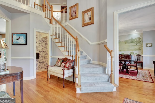 stairway with crown molding, a towering ceiling, and hardwood / wood-style floors