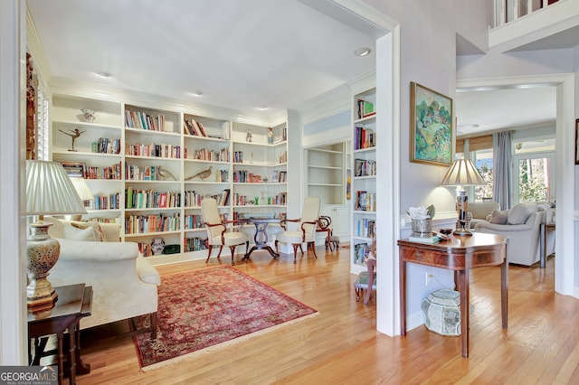 sitting room with hardwood / wood-style flooring, ornamental molding, and built in features