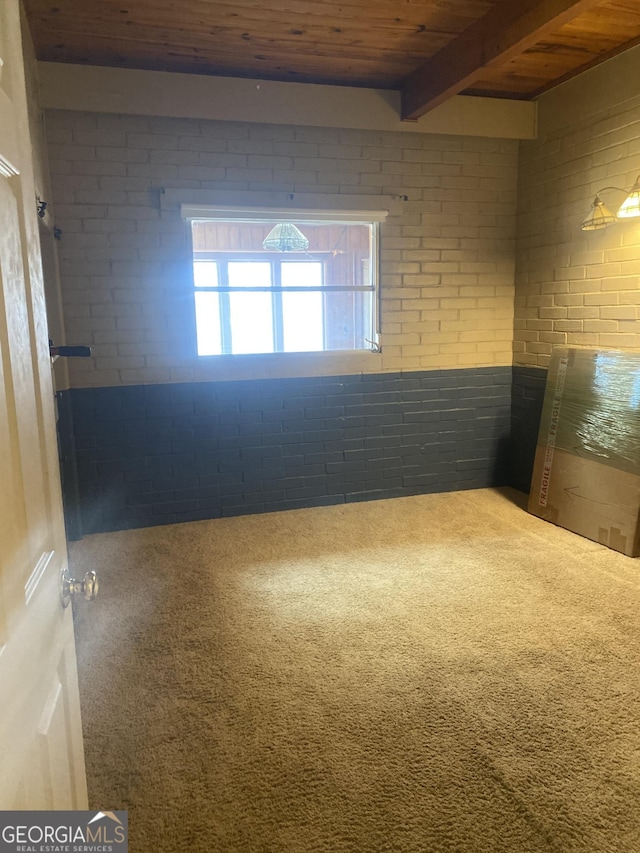 carpeted empty room with wooden ceiling, brick wall, and beam ceiling