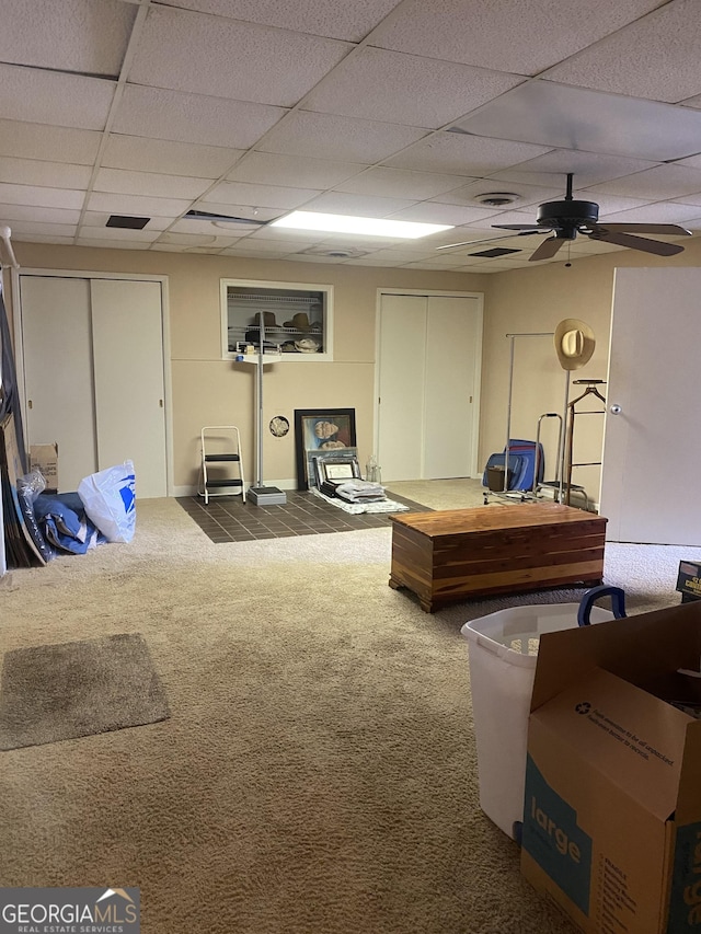 interior space featuring ceiling fan, a paneled ceiling, and carpet flooring