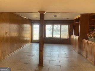 empty room featuring crown molding and wooden walls