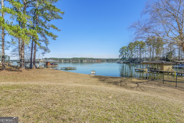 dock area with a lawn, a water view, and boat lift